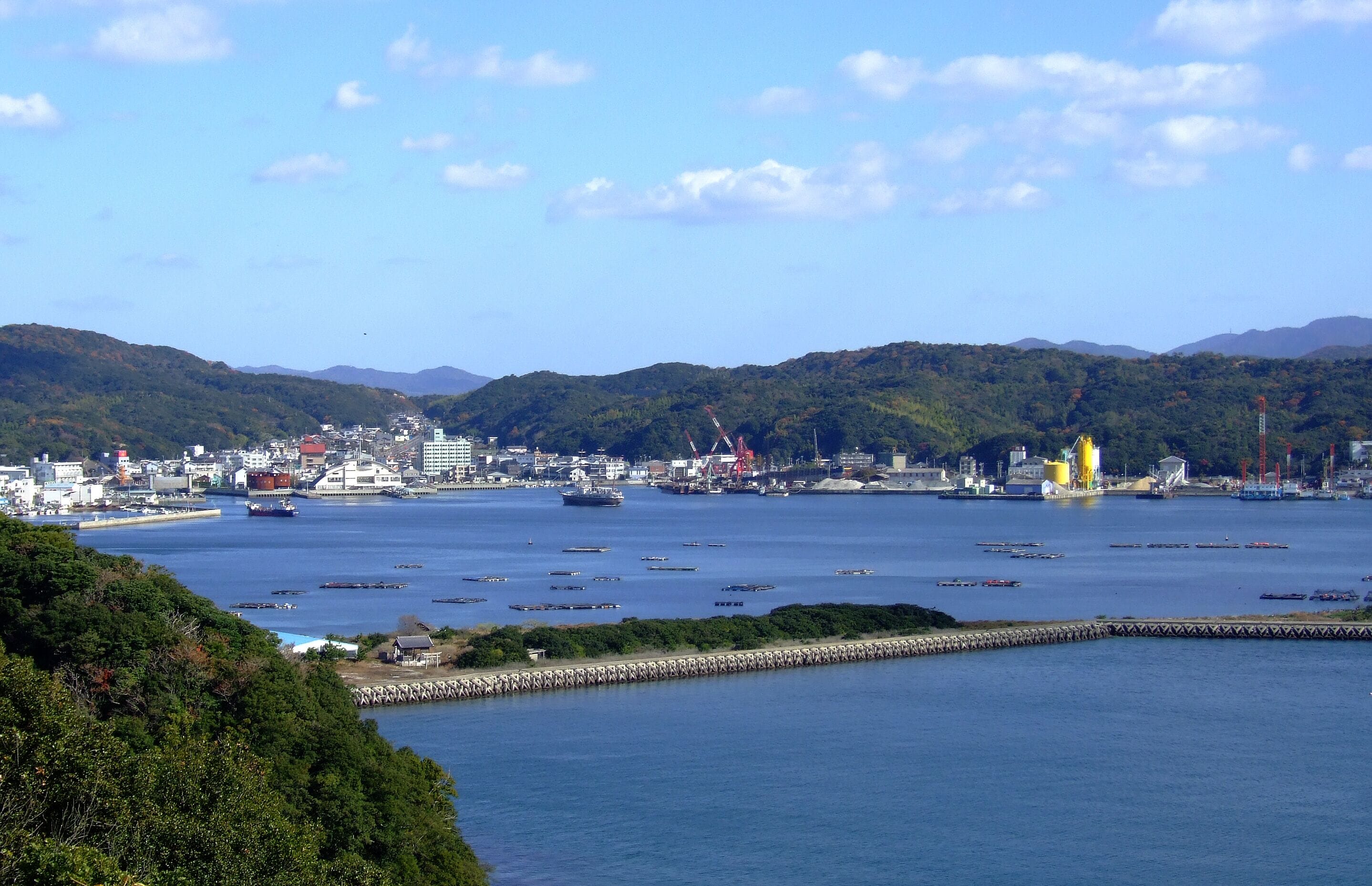 A coastal city with a harbor, ships, and industrial cranes.
