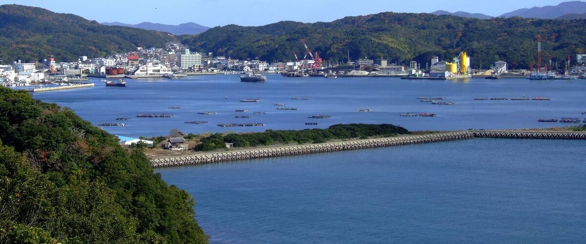 A coastal city with a harbor, ships, and industrial cranes.