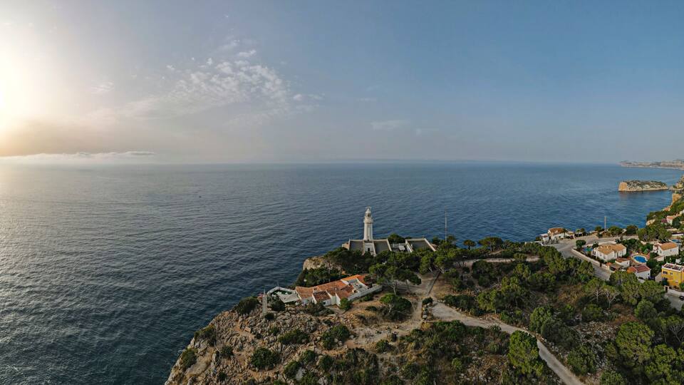 A coastal town with a lighthouse, rocky cliffs, and a clear view of the sea.