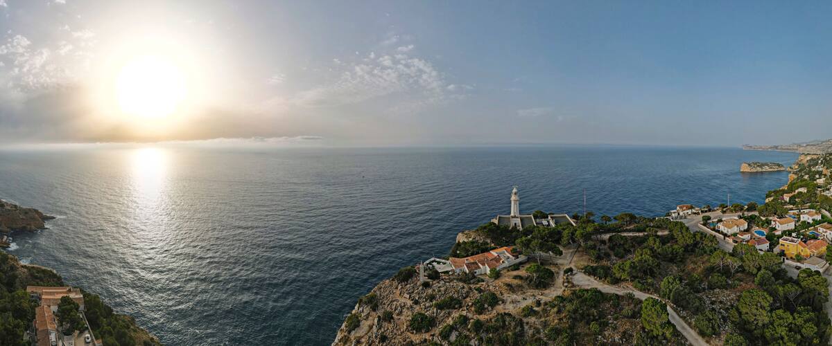 A coastal town with a lighthouse, rocky cliffs, and a clear view of the sea.