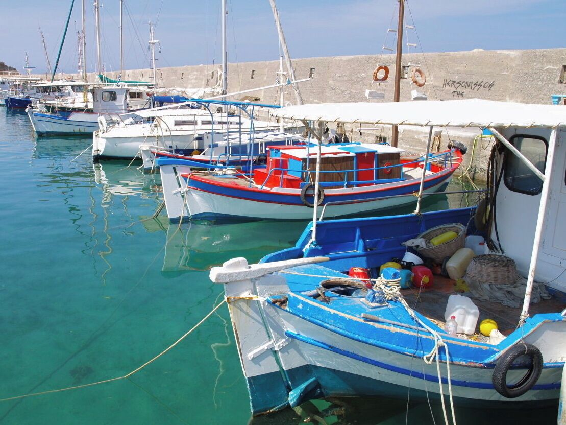 A marina with several small boats docked, a lifebuoy, and a wall with graffiti.