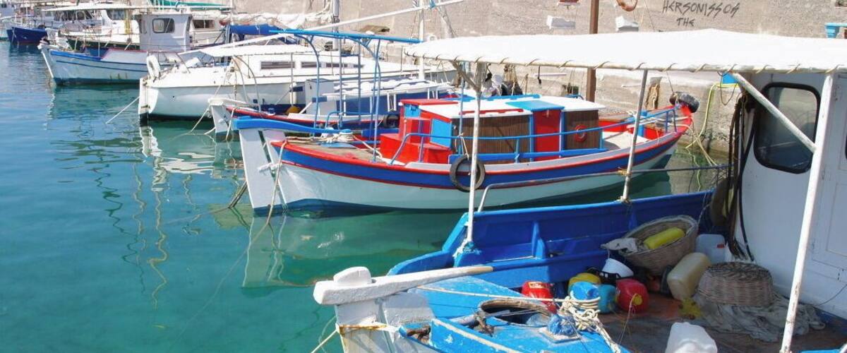 A marina with several small boats docked, a lifebuoy, and a wall with graffiti.
