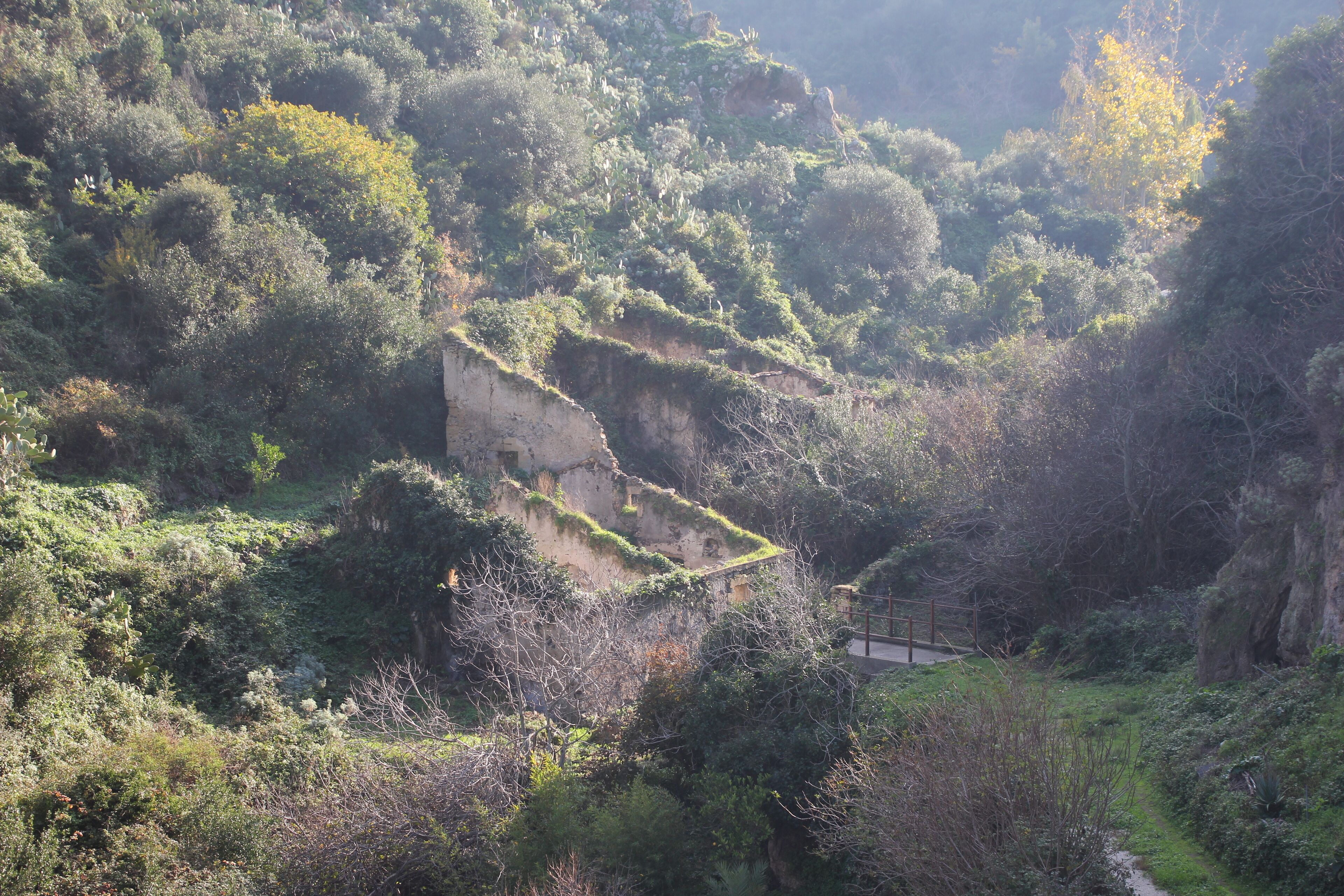 A rugged hillside with a dilapidated building and a narrow path.
