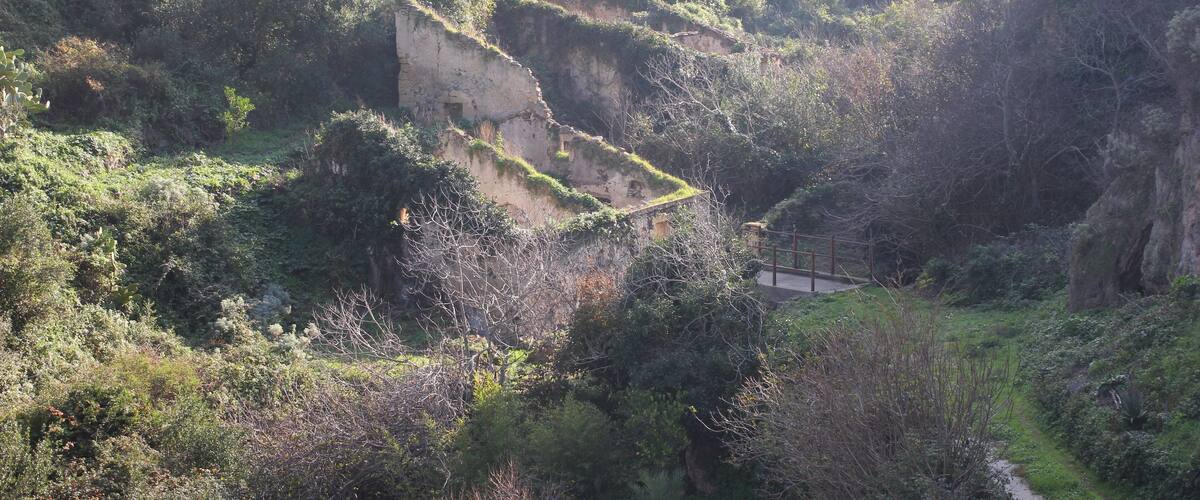 A rugged hillside with a dilapidated building and a narrow path.