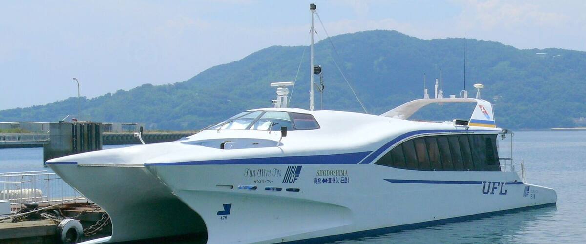 A white yacht docked at a marina with a mountainous backdrop.