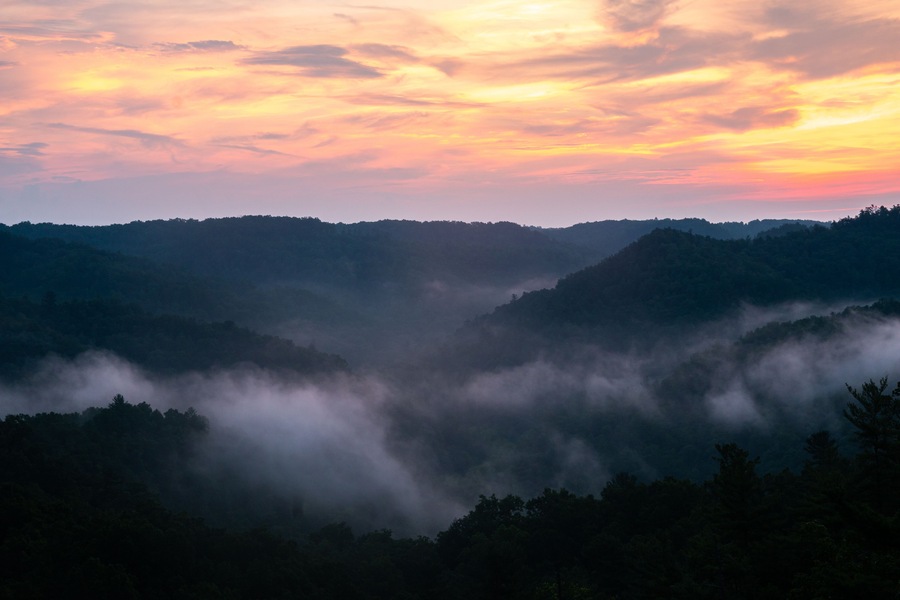 A mountainous landscape with a valley shrouded in mist.