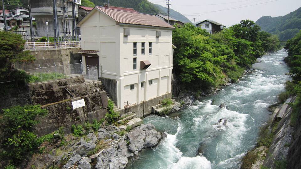 A river flowing through a mountainous area with buildings on the banks.