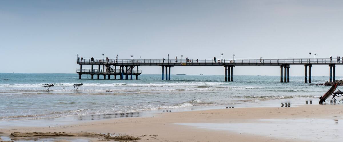 A pier extending into the ocean with people walking along it.