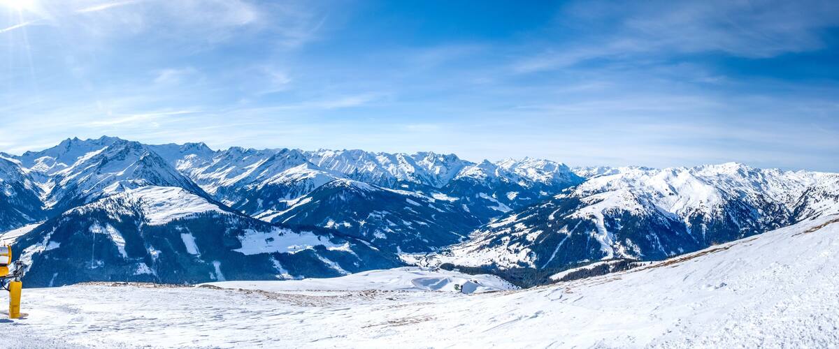 A snow-covered mountain range with a ski lift and a clear blue sky.