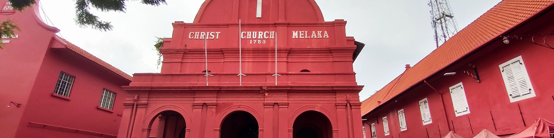 Una iglesia roja con una cruz y el nombre 'Christ Church Melaka' en su fachada.