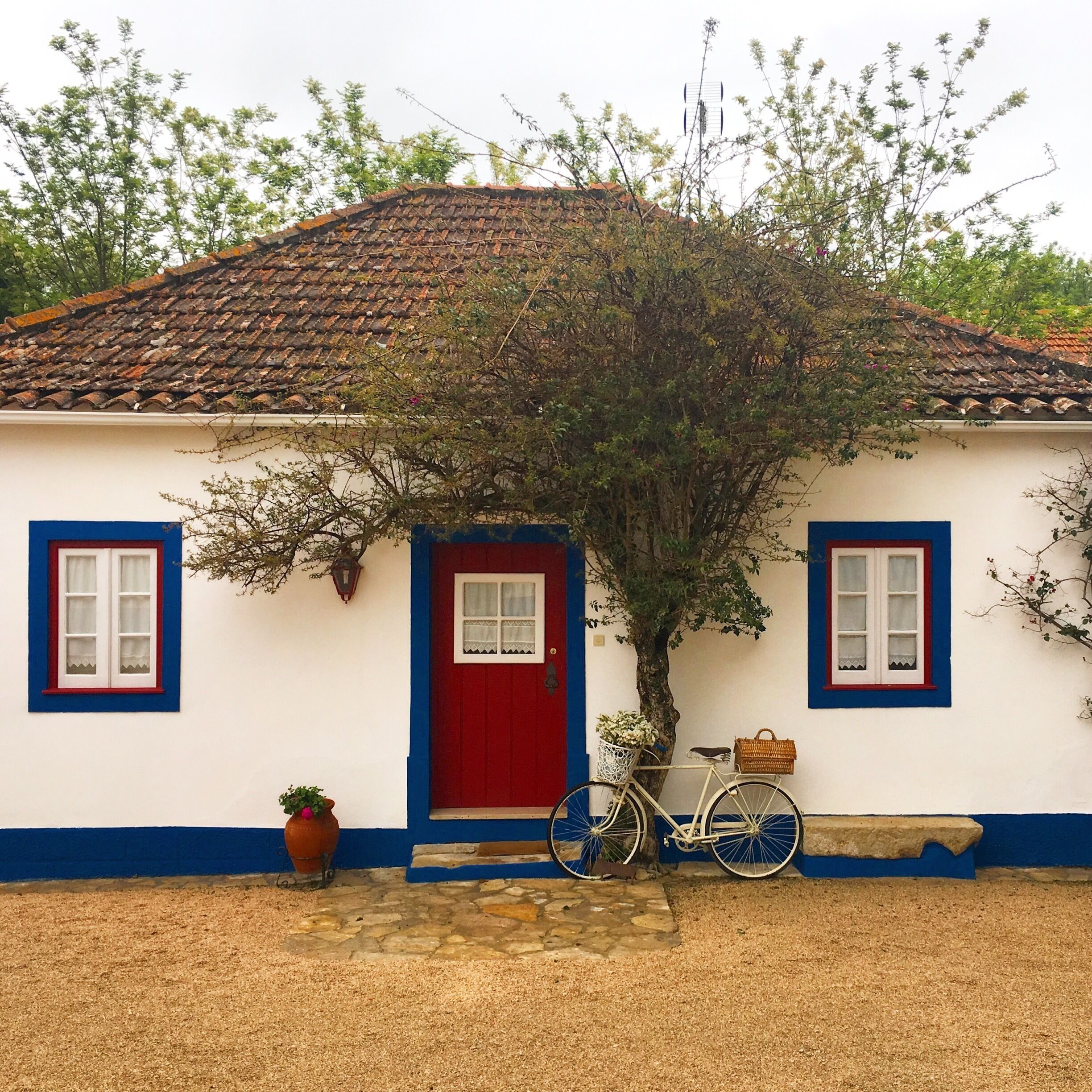 A white house with a red door, blue trim, and a tiled roof.