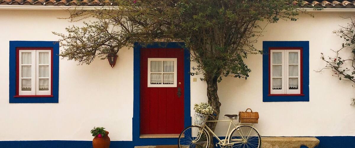 A white house with a red door, blue trim, and a tiled roof.