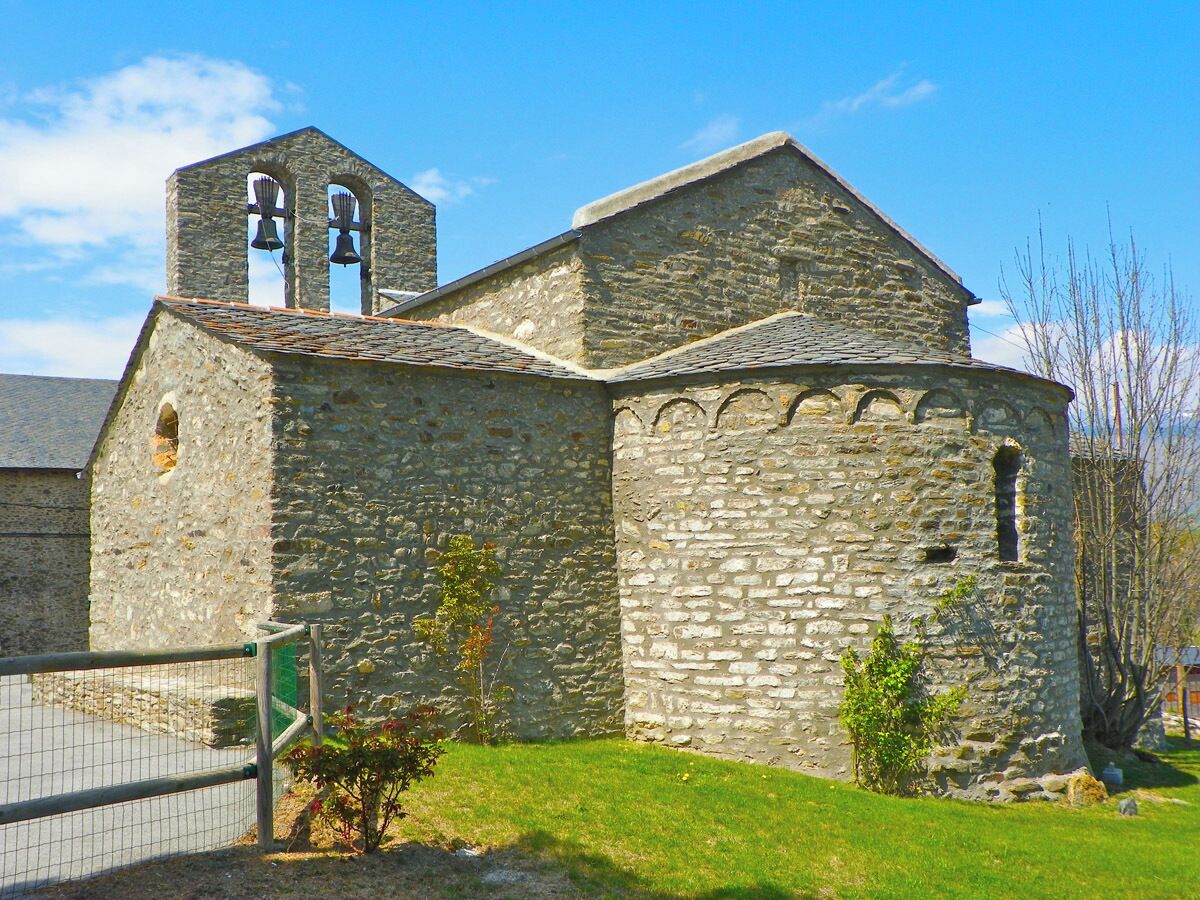 A stone church with a bell tower and a fenced area.