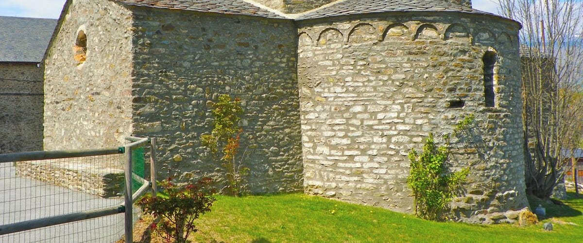 A stone church with a bell tower and a fenced area.