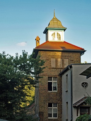 A brick building with a red roof and a tower with a pointed roof.