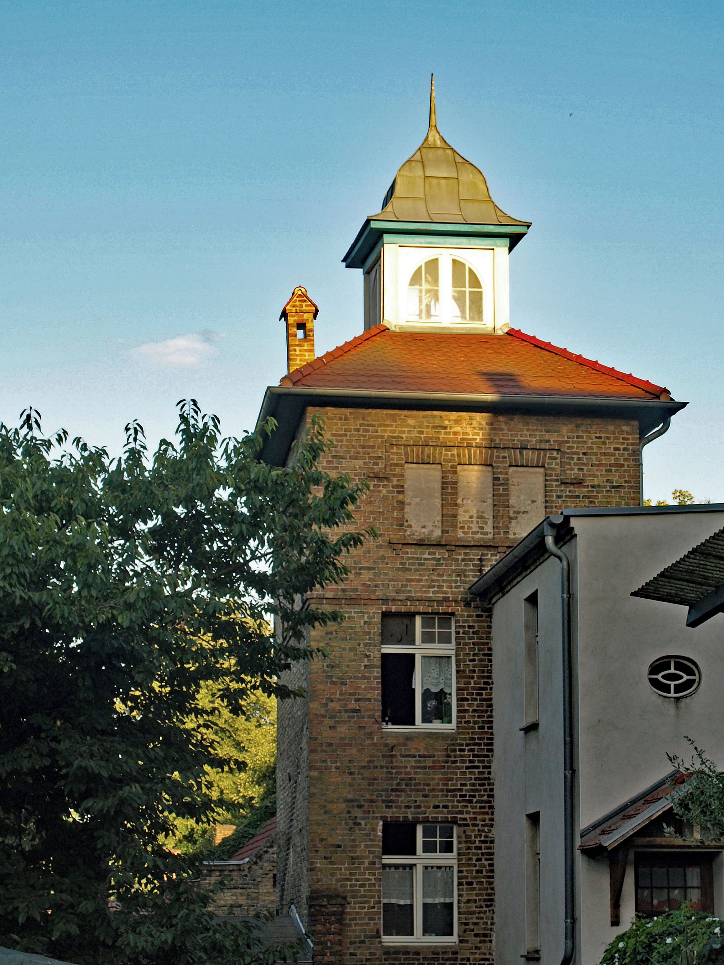 A brick building with a red roof and a tower with a pointed roof.