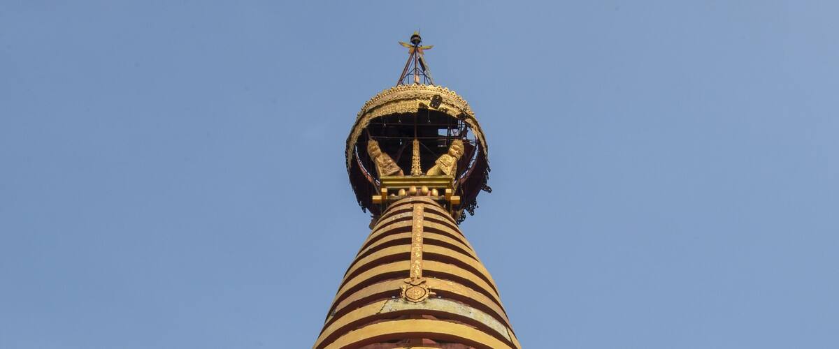 A large white stupa with a golden spire and a golden statue at its base.