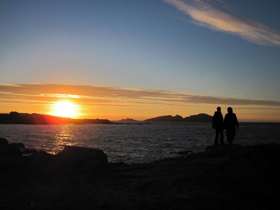 Have you experienced a 24 hour day? Hovden, on the island of Bø in Norway, is one of the places folks head to to watch the sun descend, arc against the horizon, and climb back up the other side. There are no mountains to mask the midnight sun, just open ocean. I cycled there with a couple of new friends this past summer. It was chilly, but we found ourselves taking off our shoes, increasing the sense of connection with the ground bellow us as we watched the sky above swing past. 
Have a look here for another one of my experiences soaking in the dramatic lighting of summer in the arctic: 
http://www.regenevieve.com/blog/norwegian-moments-moody-skies-dramatic-lighting/