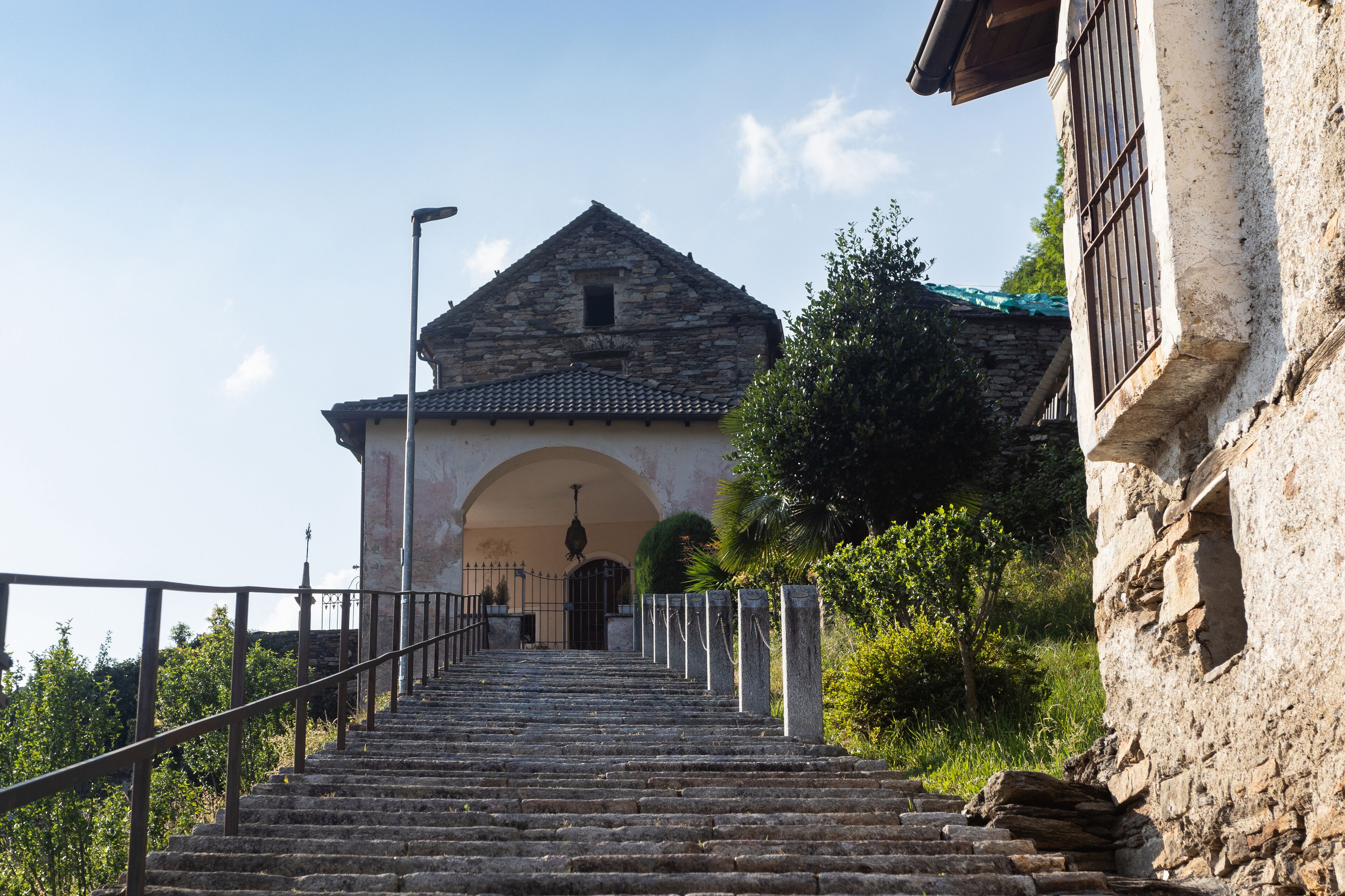 A stone staircase leading to a building with a tiled roof and an arched entrance.