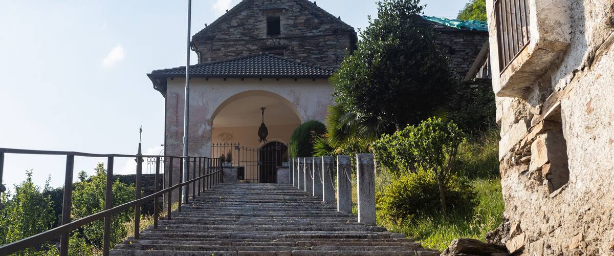 A stone staircase leading to a building with a tiled roof and an arched entrance.