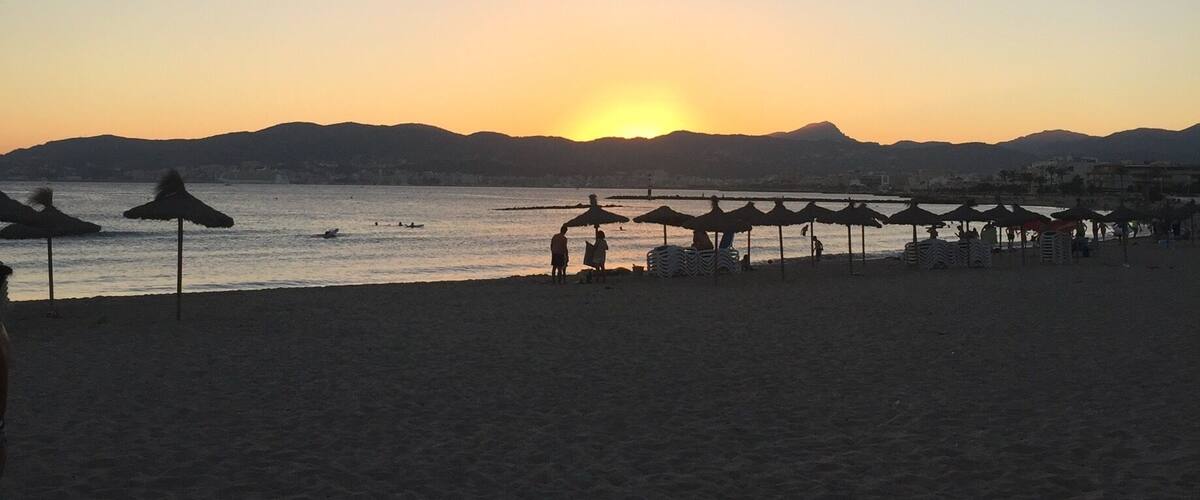 A beach at sunset with a pier extending into the water.