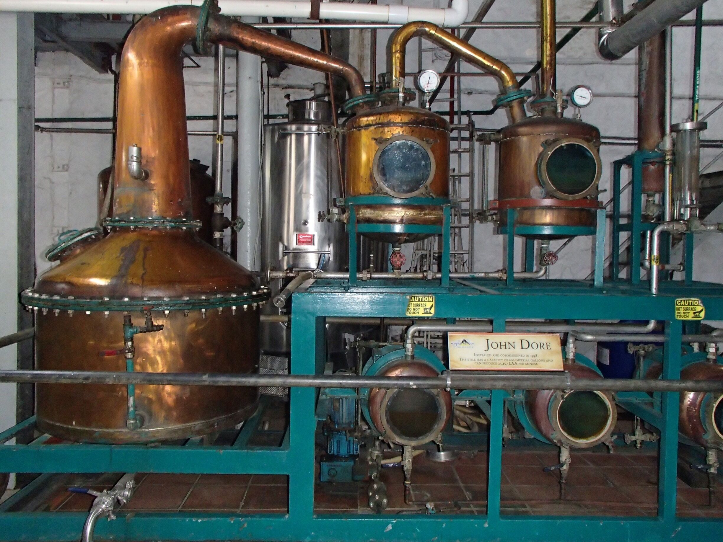 A distillation apparatus with copper components and a sign reading "John Doe".