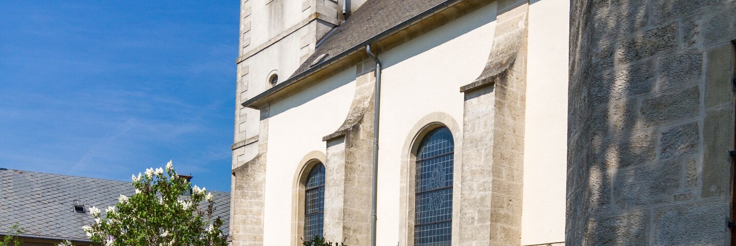A church with a bell tower and a statue in the courtyard.