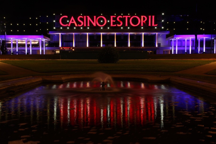 A casino with a fountain in front, illuminated by purple lights.