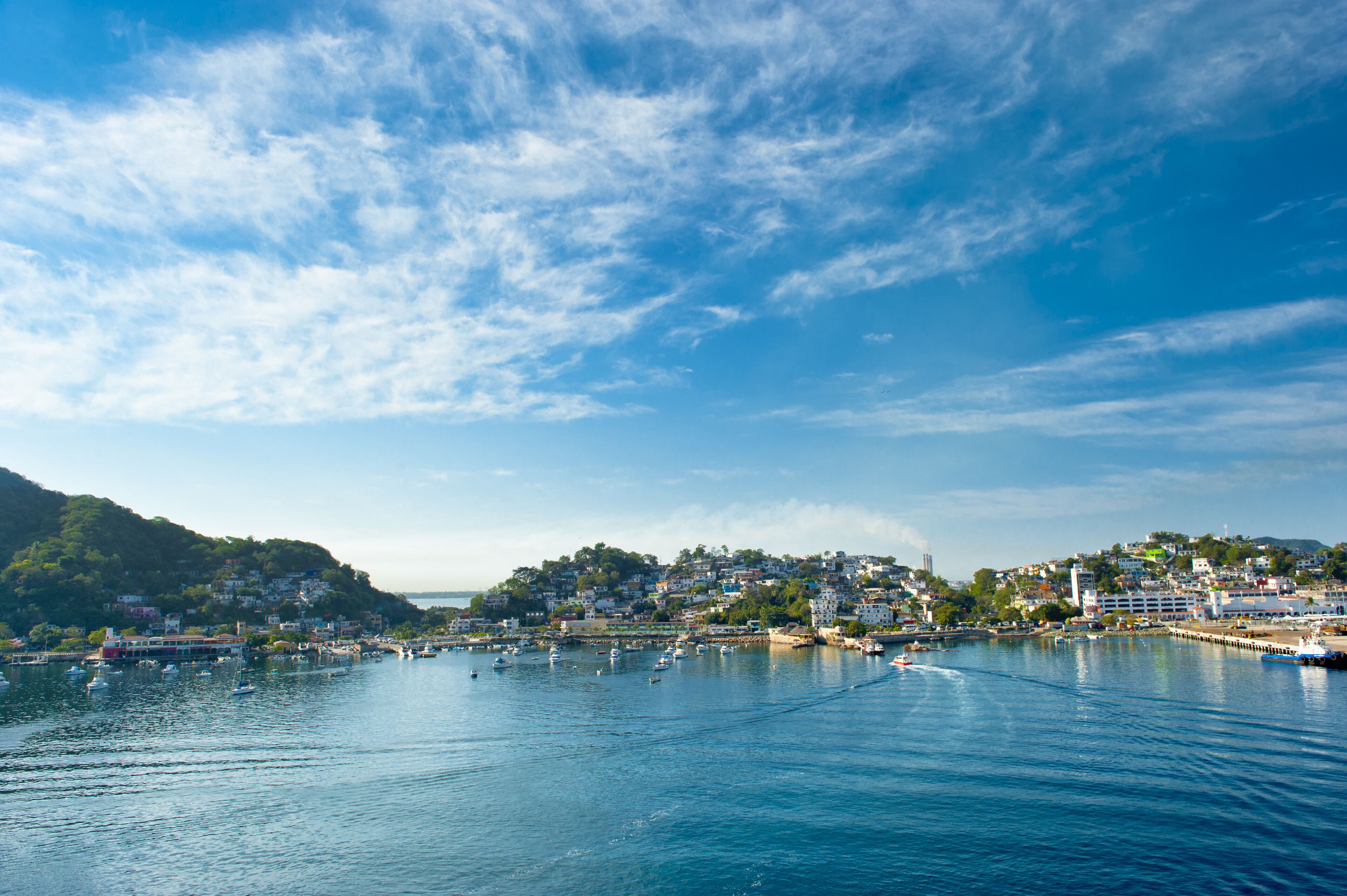 A coastal town with a harbor, boats, and buildings on a hillside.