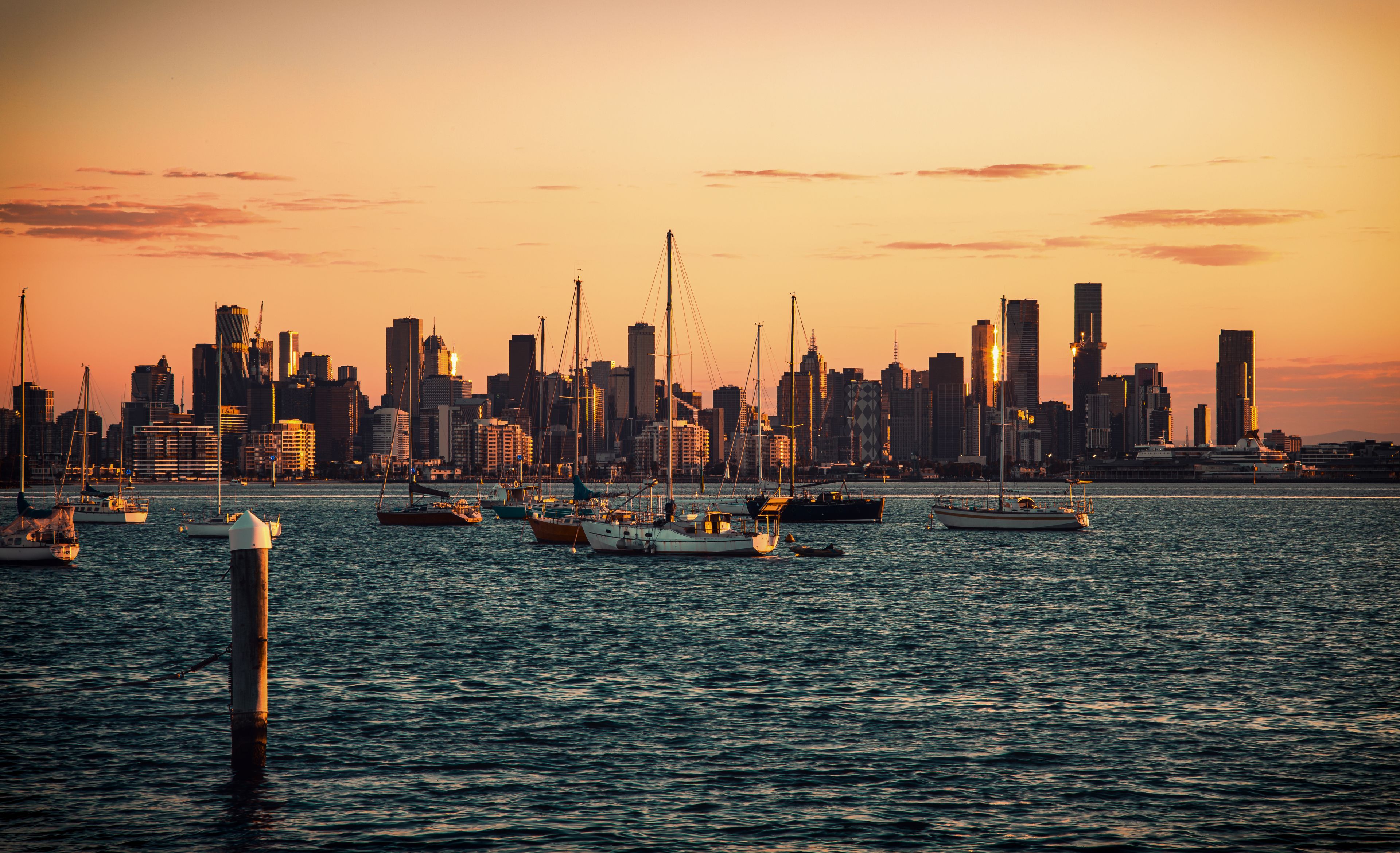Un horizonte urbano al atardecer con barcos en el agua.