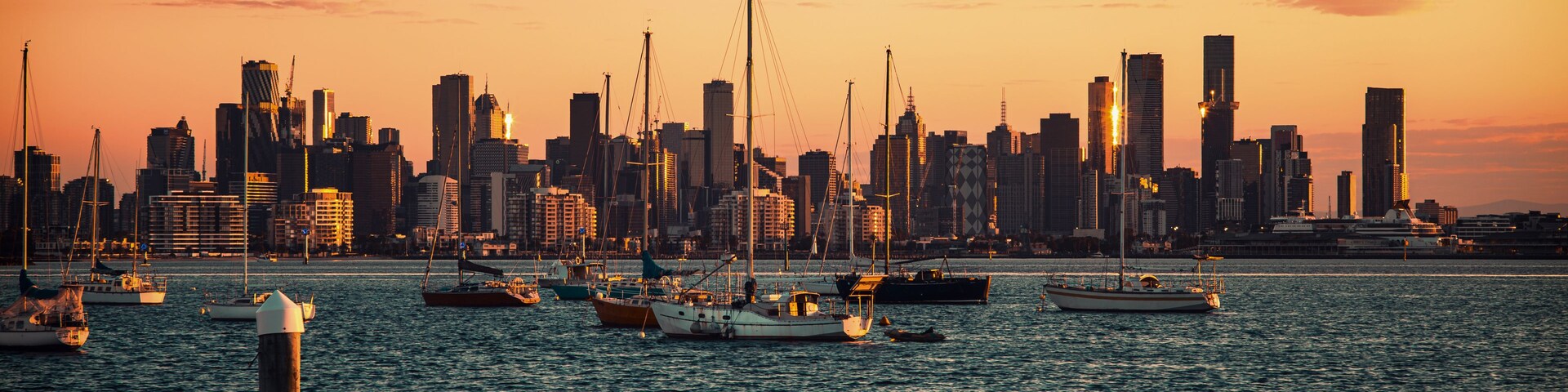 Un horizonte urbano al atardecer con barcos en el agua.