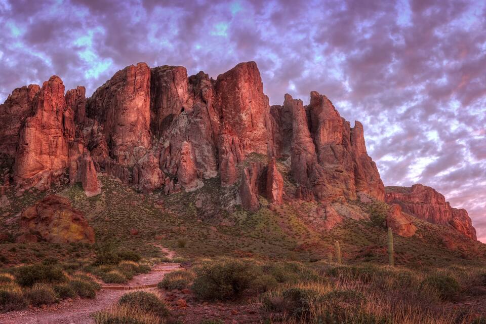 A rocky mountain range with a path leading up to it.