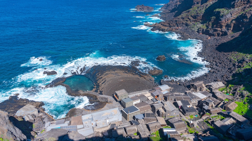 A coastal village with traditional stone buildings, a rocky shoreline, and the ocean.