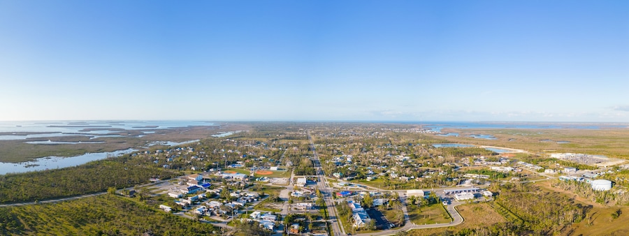 An aerial view of a coastal town with residential areas, a baseball field, and a large body of water.