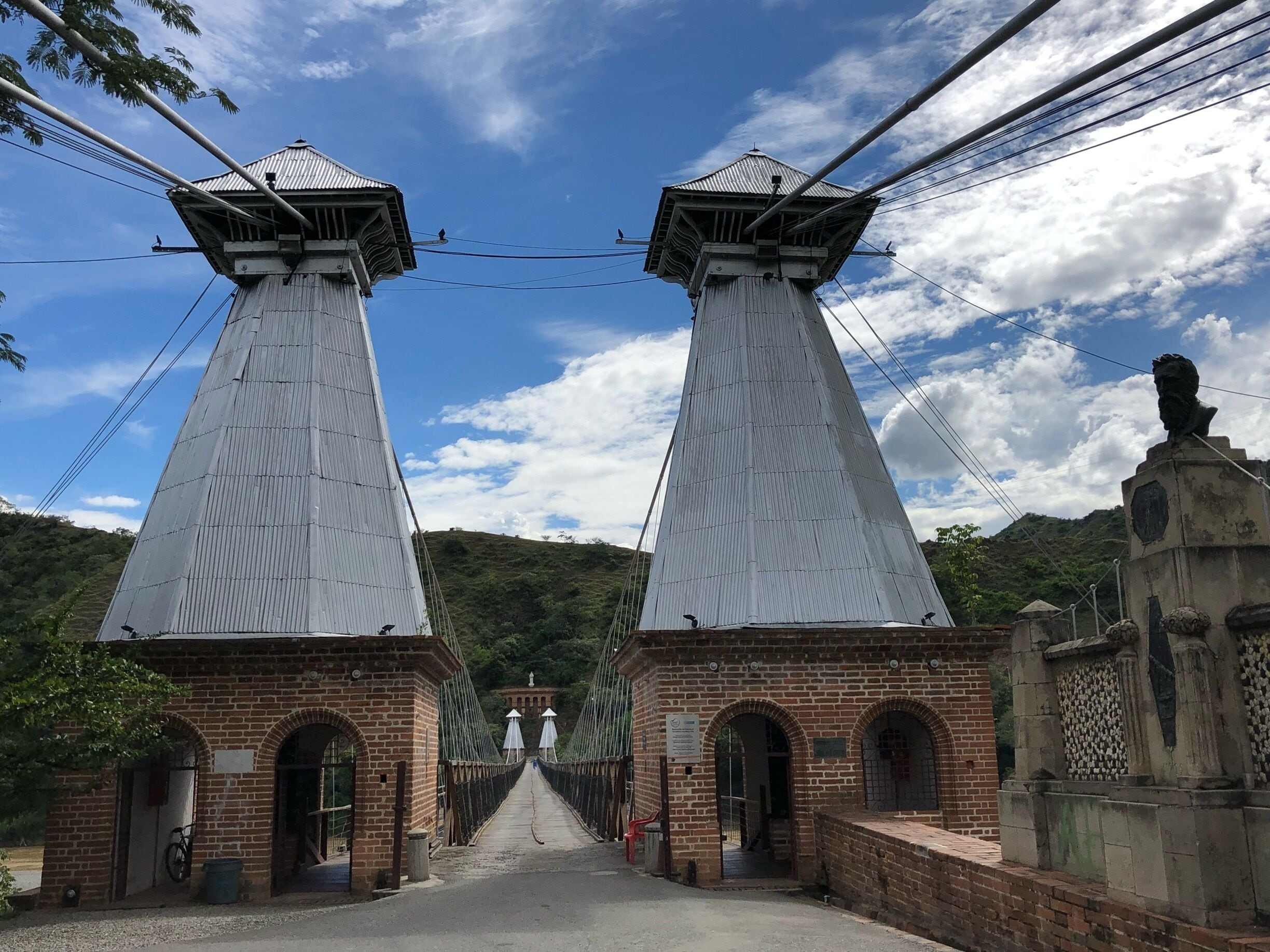 A suspension bridge with two towers and a brick building at the end.
