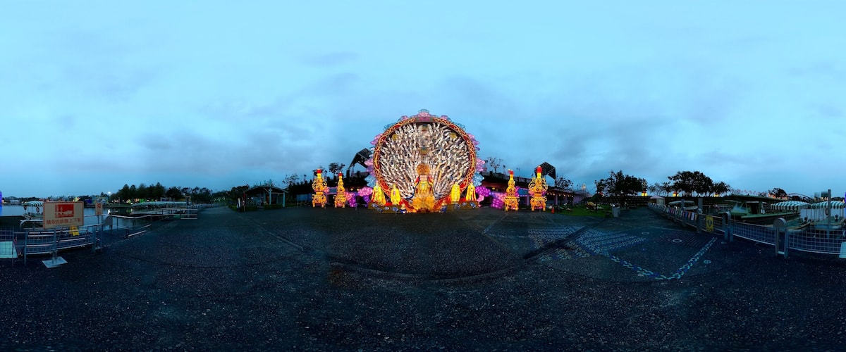 A Ferris wheel with colorful lights and decorations at dusk.