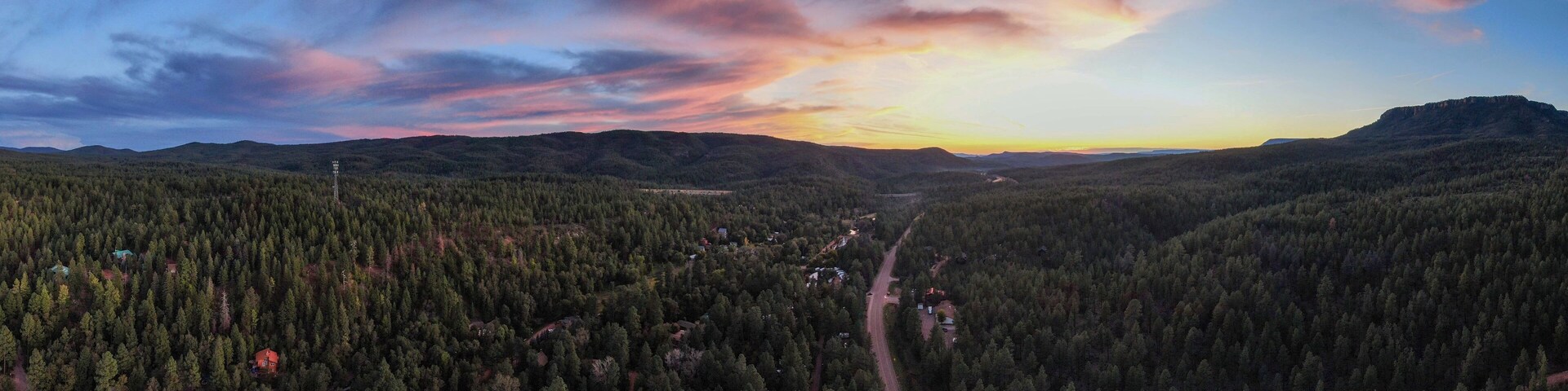 Um vale arborizado com uma estrada sinuosa e uma montanha ao longe.