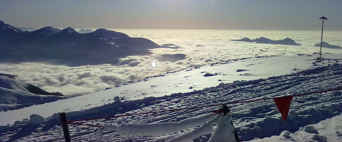 A snowy mountain landscape with a clear sky and the sun shining brightly.