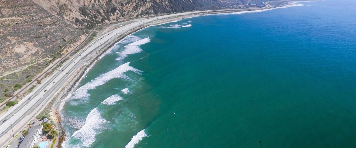 A coastal highway with cliffs and ocean waves.