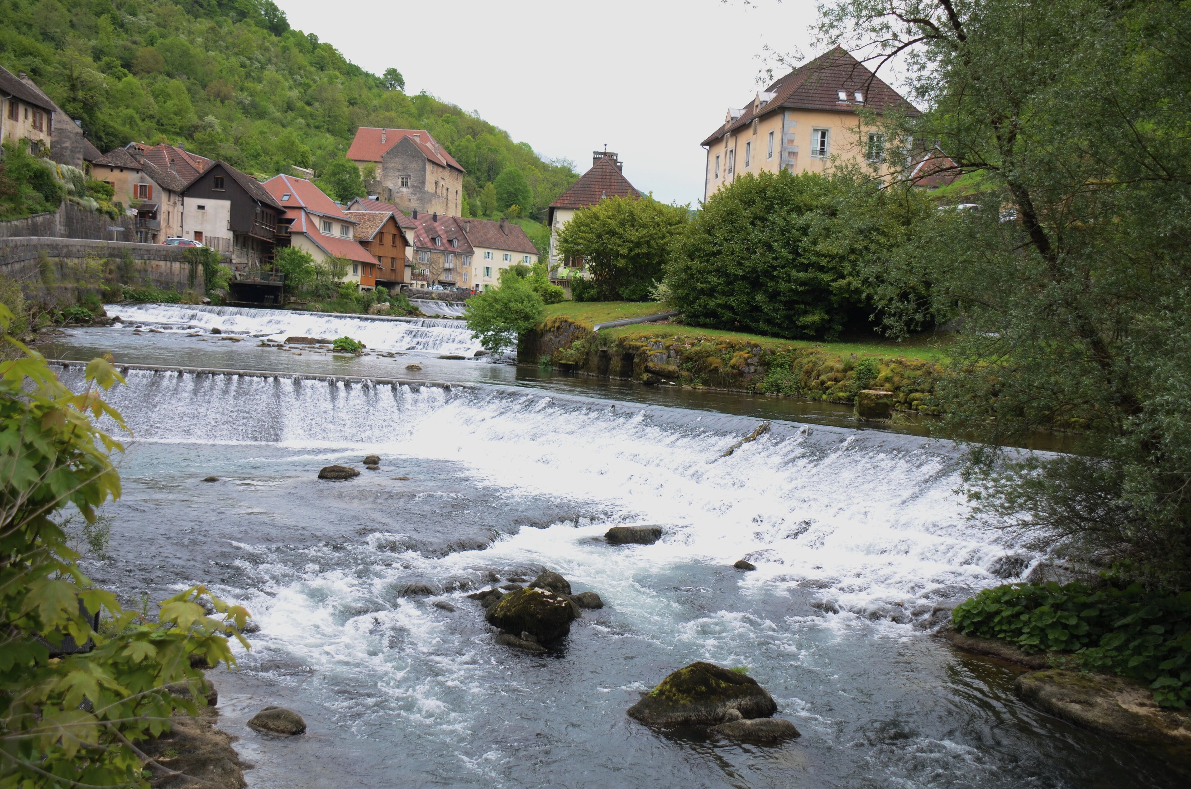 A river flowing through a town with houses and a waterfall.