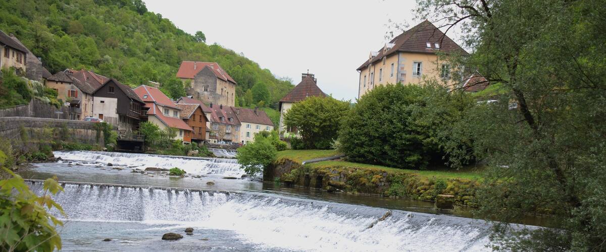 A river flowing through a town with houses and a waterfall.