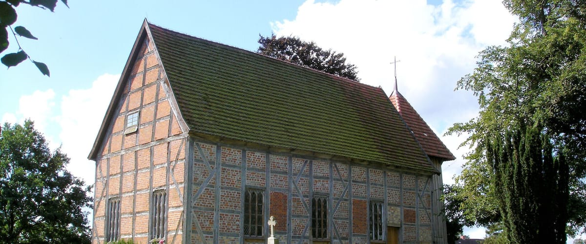 A traditional half-timbered house with a steep roof, surrounded by a well-maintained lawn and hedges.