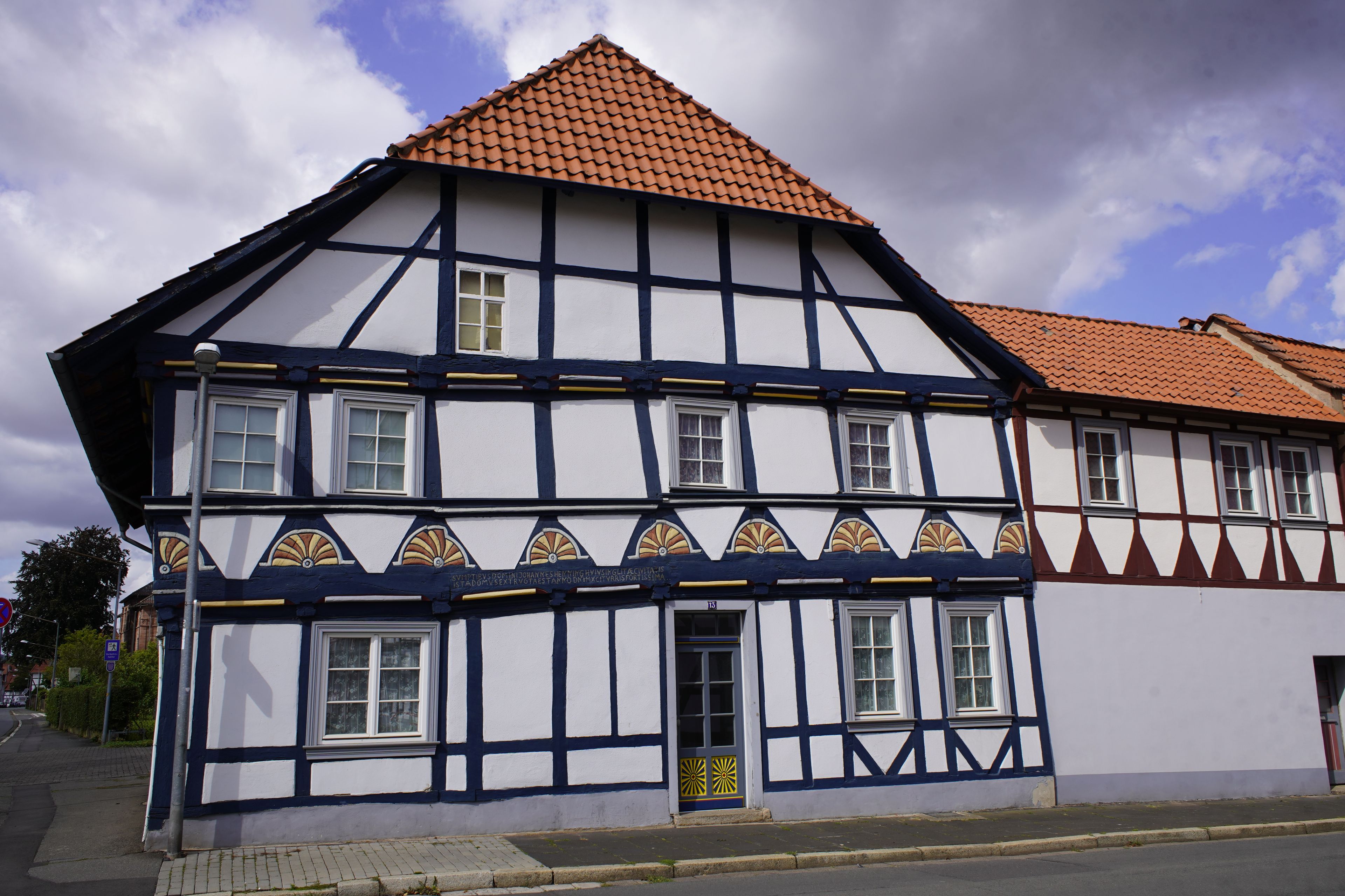 A traditional half-timbered house with a red-tiled roof and white walls.