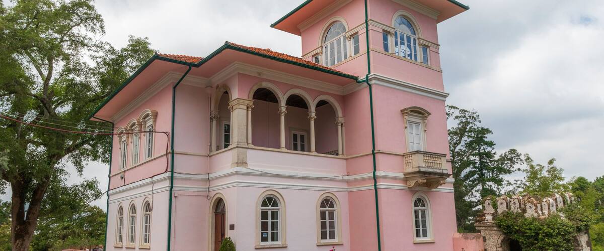A pink building with arched windows and a tower.