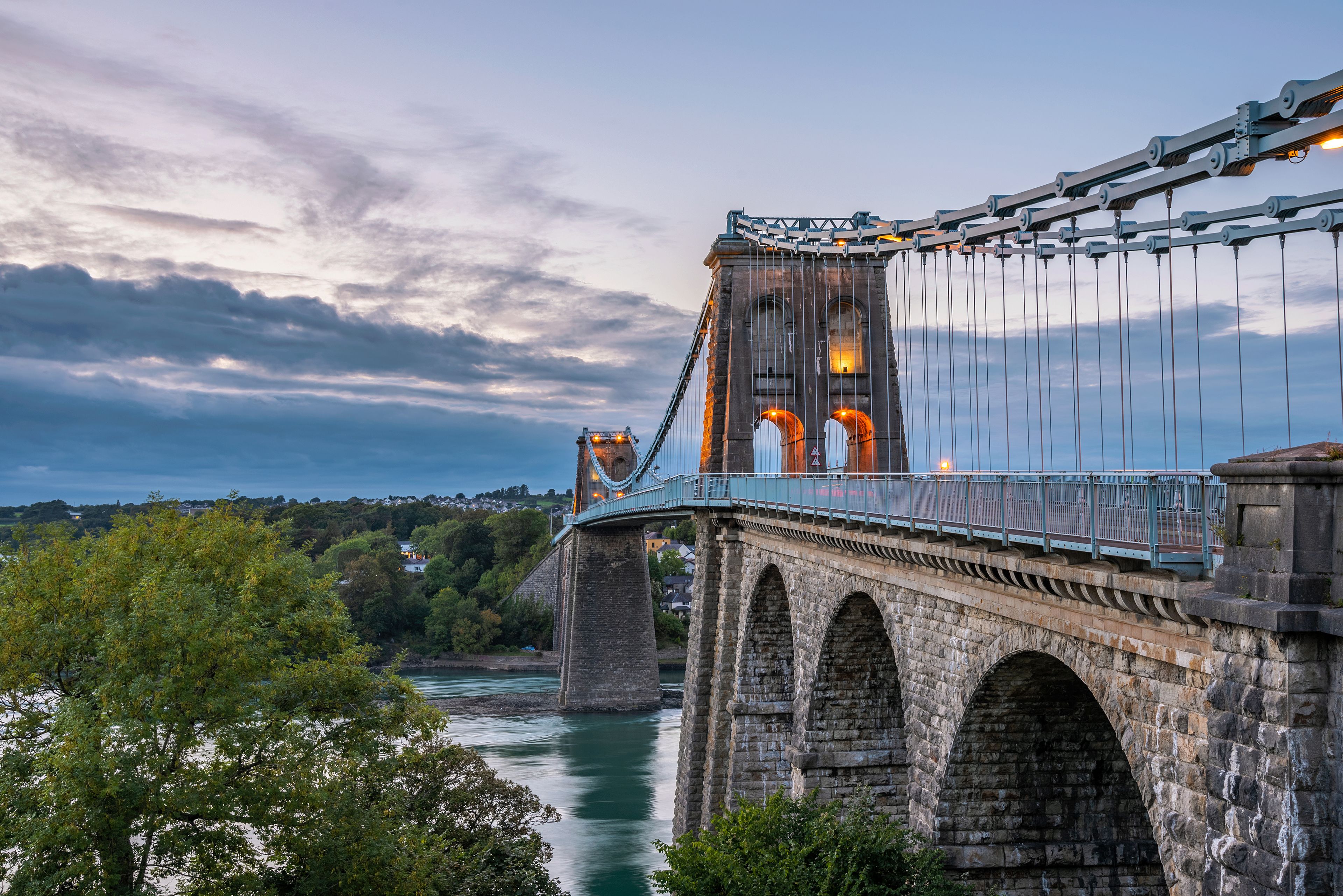 A suspension bridge with stone towers and a river below.