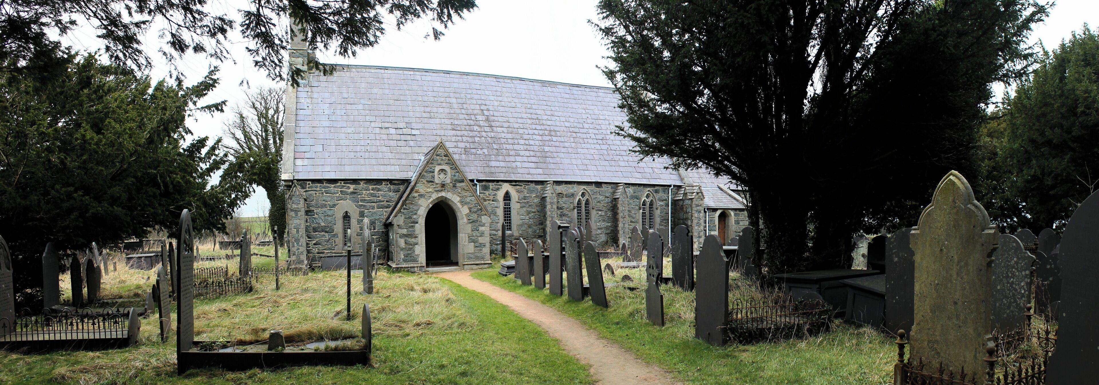 A stone church with a curved roof and a graveyard with headstones.