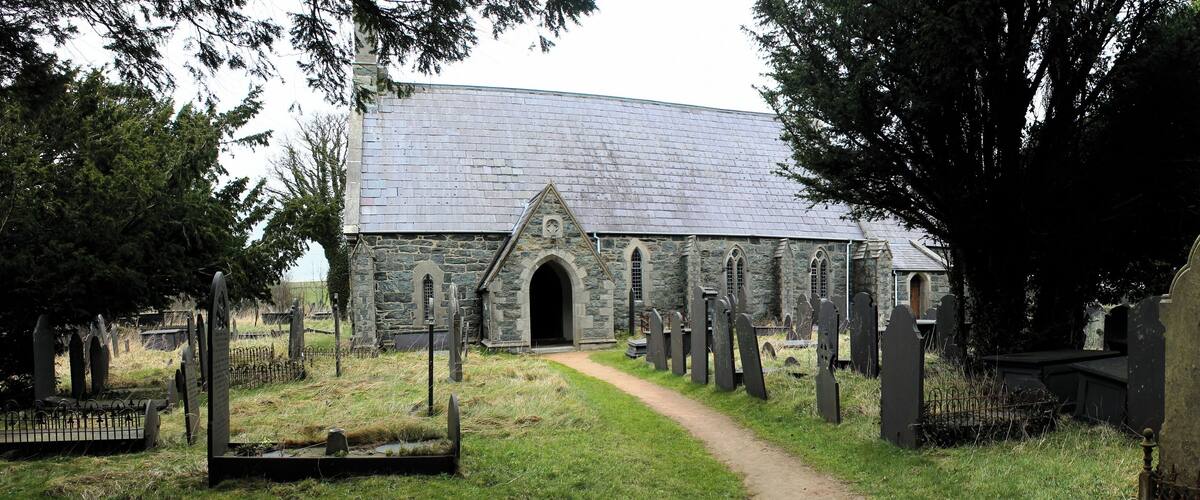 A stone church with a curved roof and a graveyard with headstones.