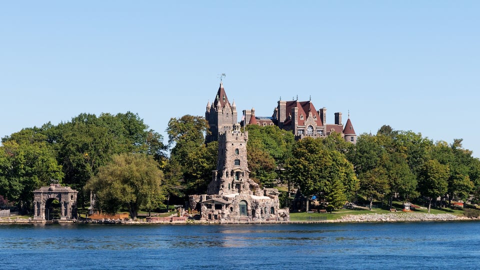 A historic castle surrounded by lush greenery and a calm lake.