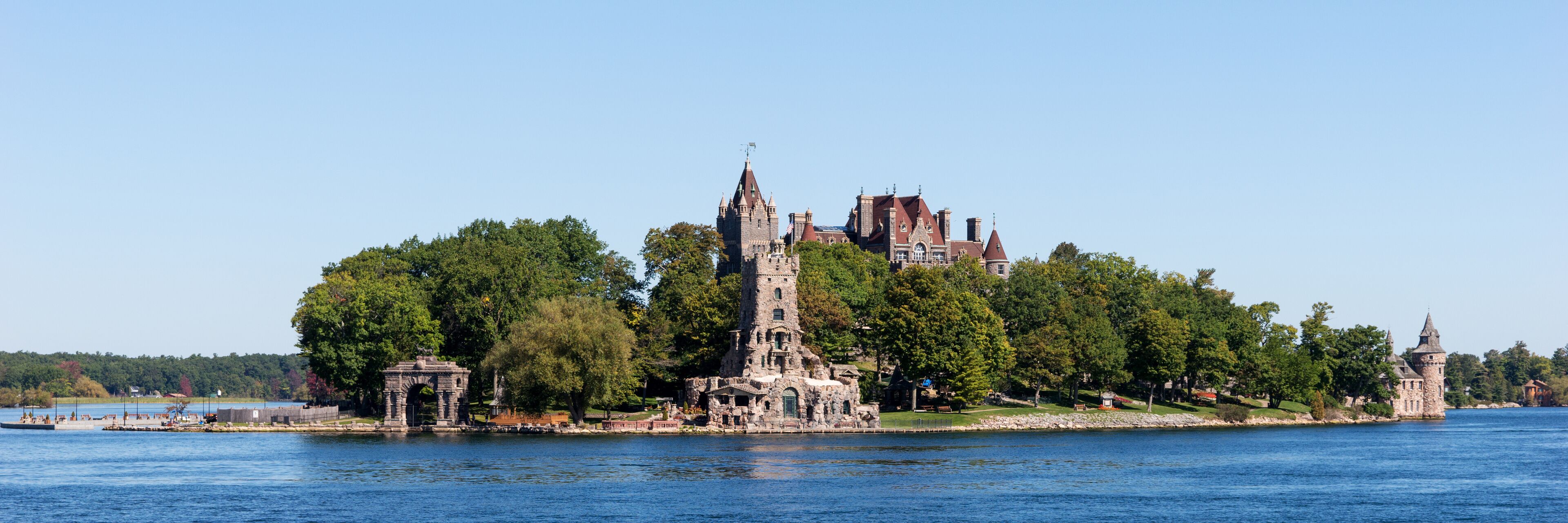 A historic castle surrounded by lush greenery and a calm lake.