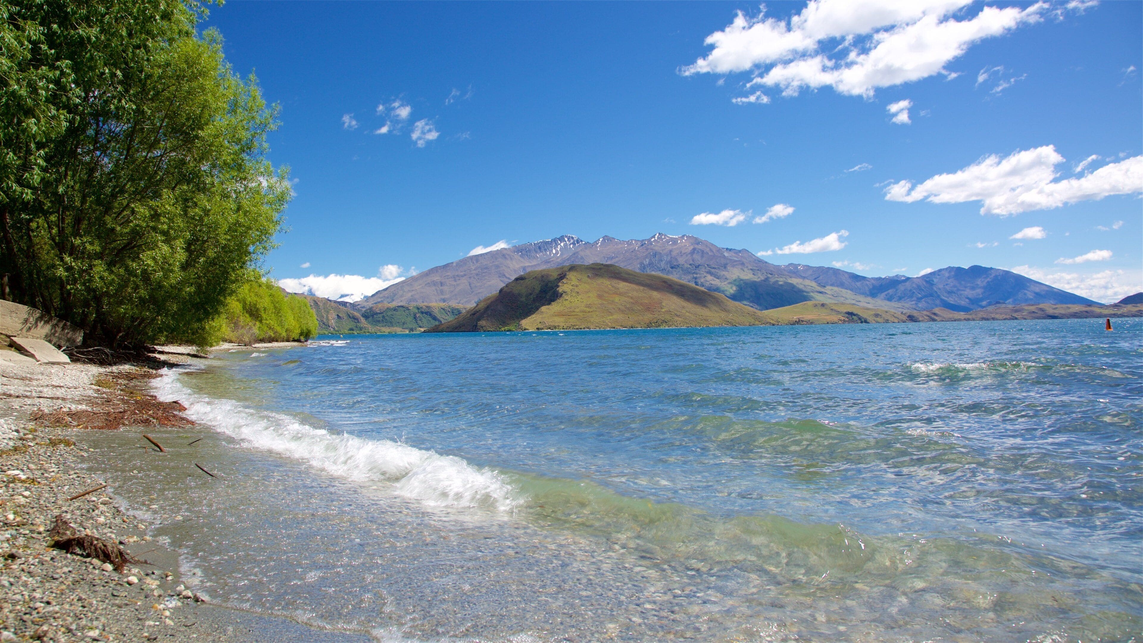 Wanaka som viser en sø eller et vandhul, en stenstrand og bjerge